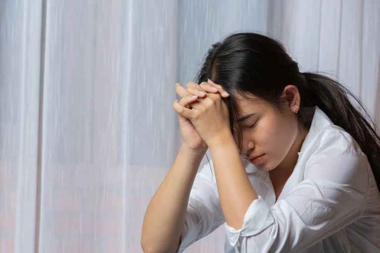 A woman sitting alone looking upset, illustrating emotional avoidance when facing new or stressful situations.