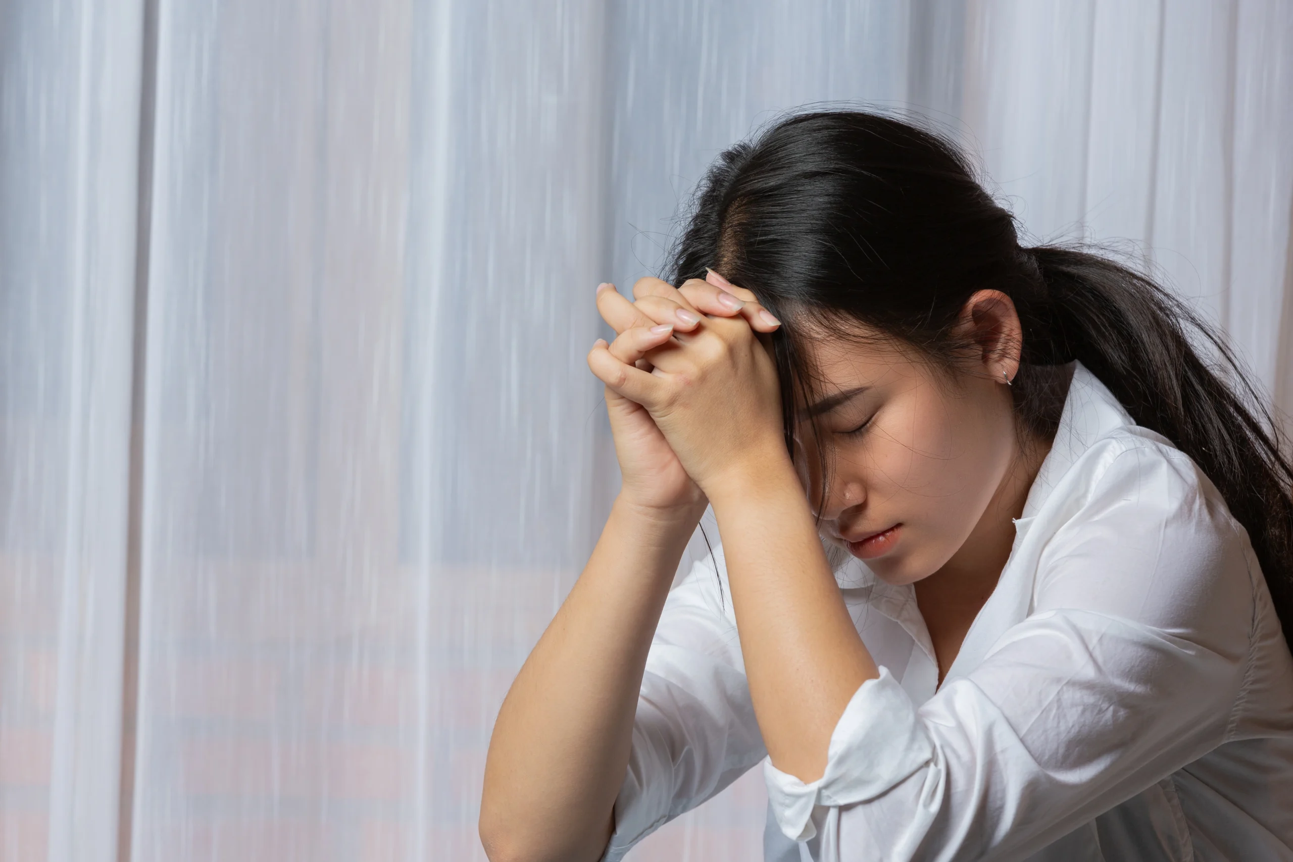 A woman sitting alone looking upset, illustrating emotional avoidance when facing new or stressful situations.