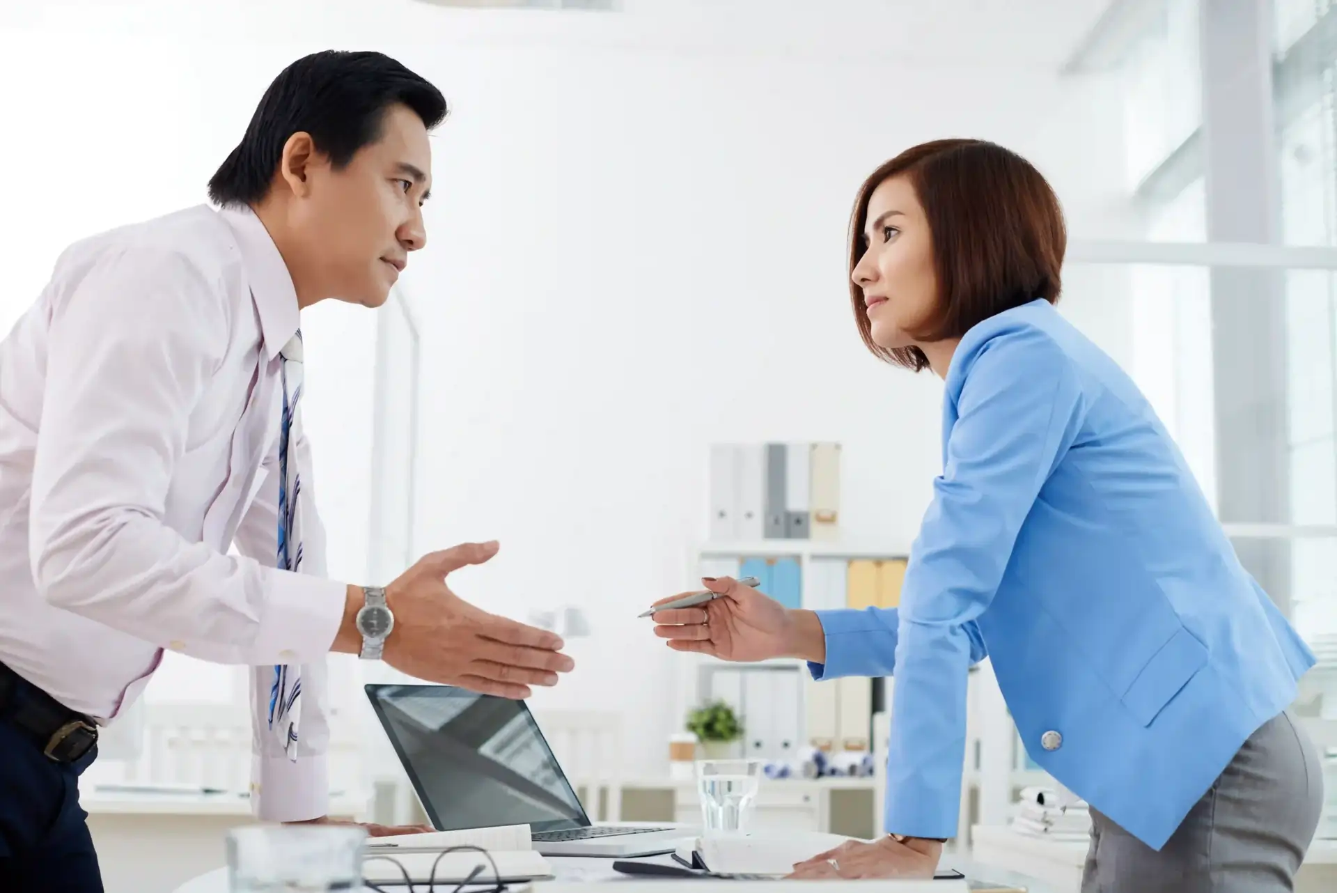 Two business professionals having a serious and respectful discussion in an office, representing constructive communication and high - EQ opposition that fosters cooperation.