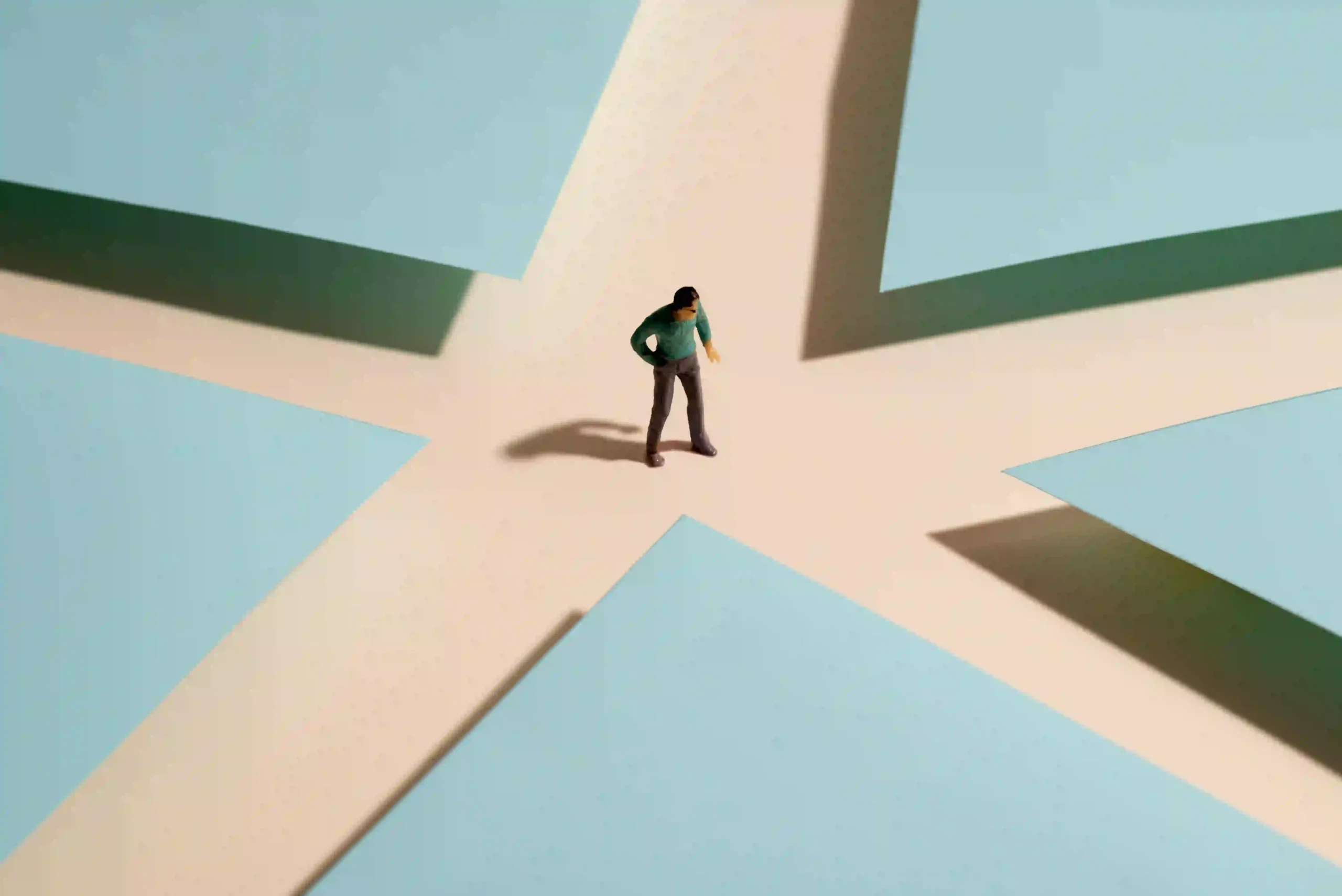 A miniature figure standing at a crossroads formed by geometric shapes, symbolizing the choice between staying in the comfort zone and stepping into growth.